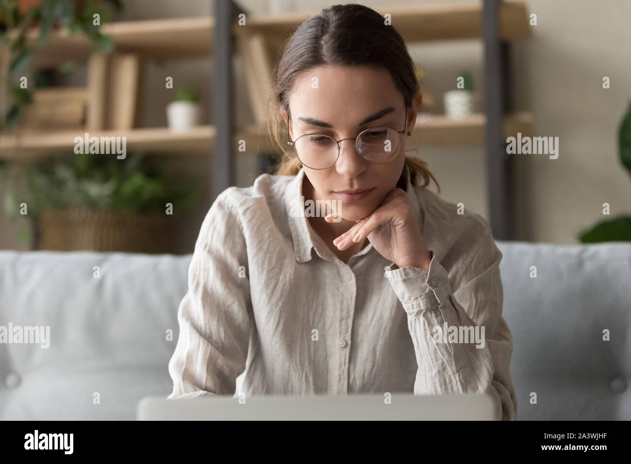 Focused thoughtful female freelancer working on laptop at home Stock Photo