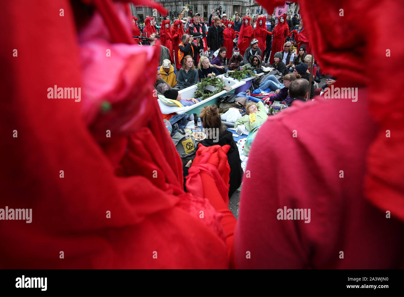 The red rebels encircle protesters in bathtubs in Trafalgar Square during the fourth day of an Extinction Rebellion (XR) protest in Westminster, London. Stock Photo