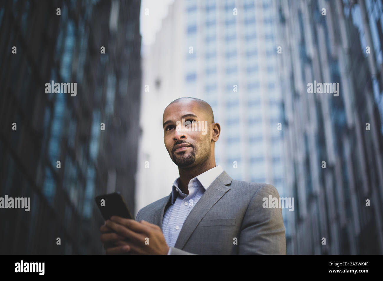 Businessman walking in city using smartphone Stock Photo