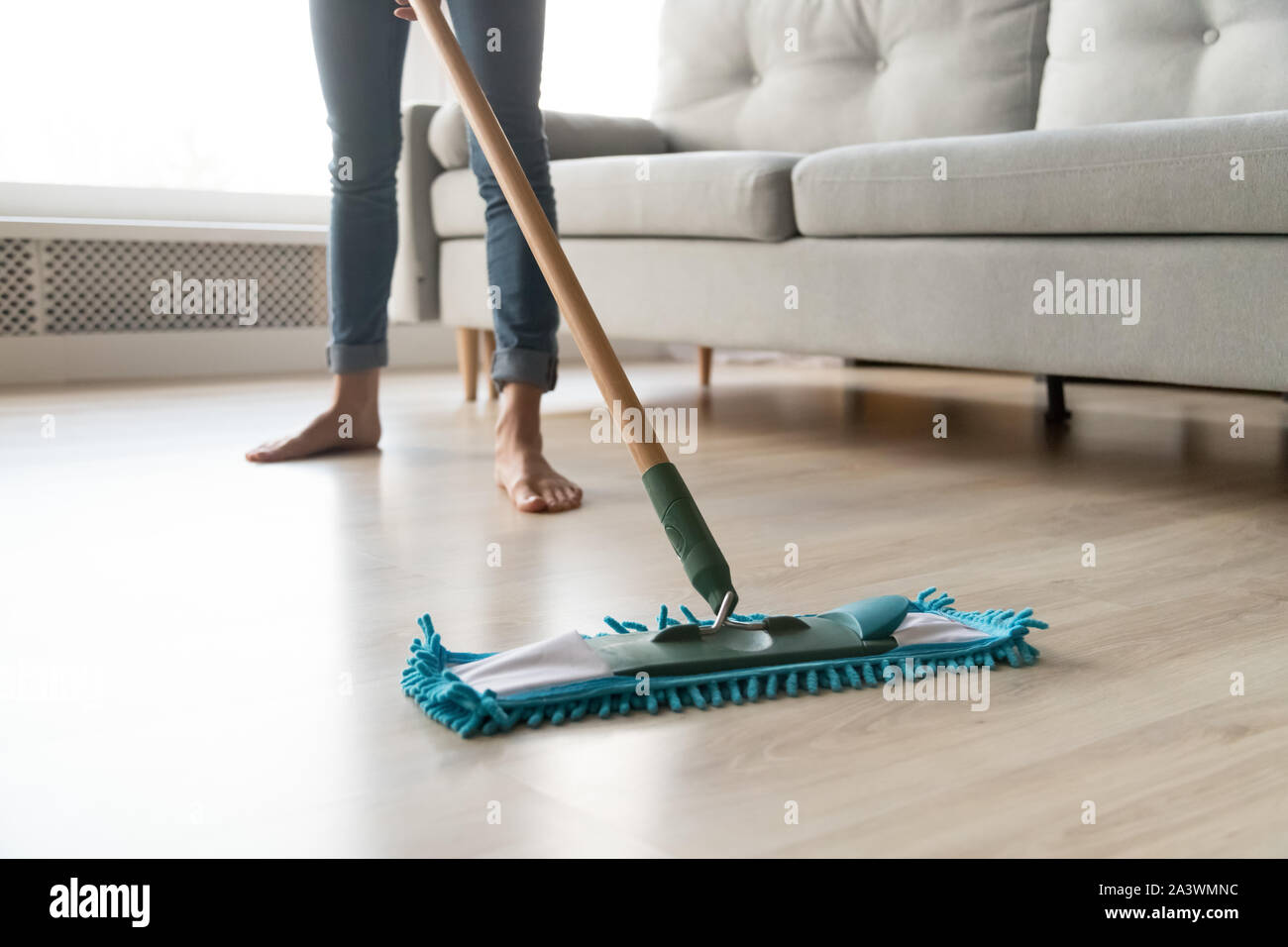 Woman housewife holding mop cleaning floor at home, close up Stock Photo