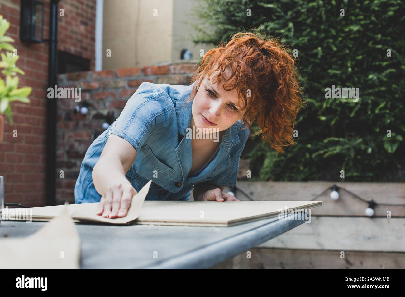Mid adult female sanding a wood in garden Stock Photo