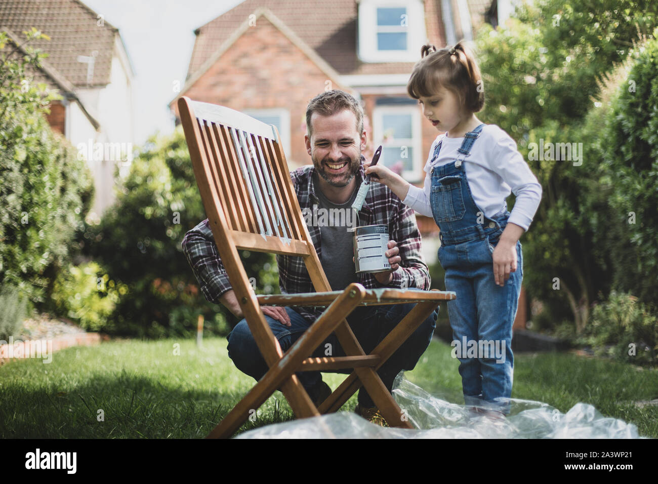 Father and Daughter painting garden furniture together Stock Photo