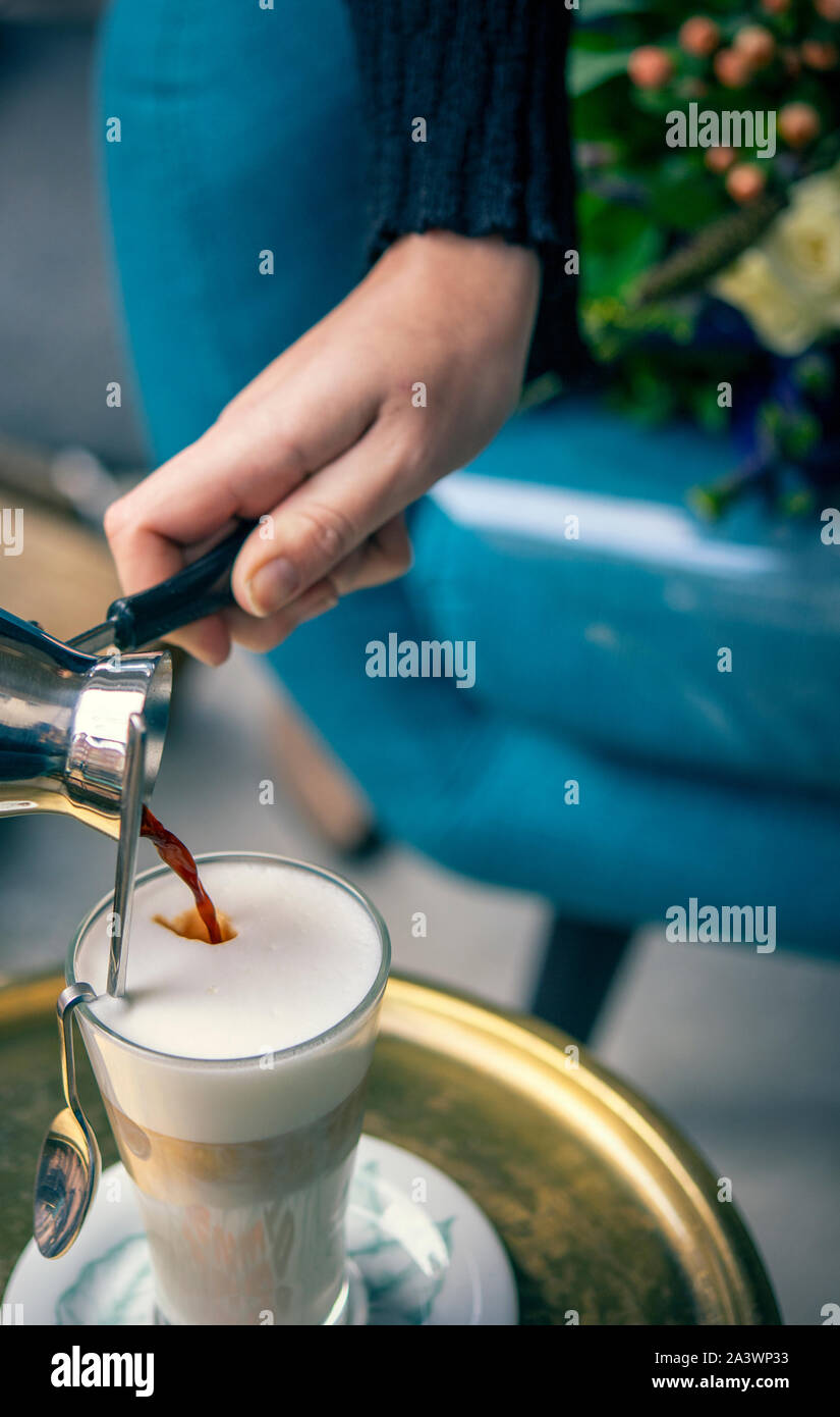 Waitress pouring a fresh latte coffee in a cafe Stock Photo