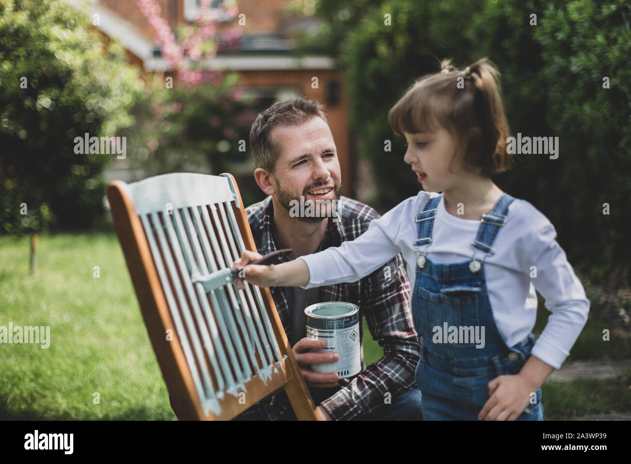 Father and Daughter painting garden furniture together Stock Photo