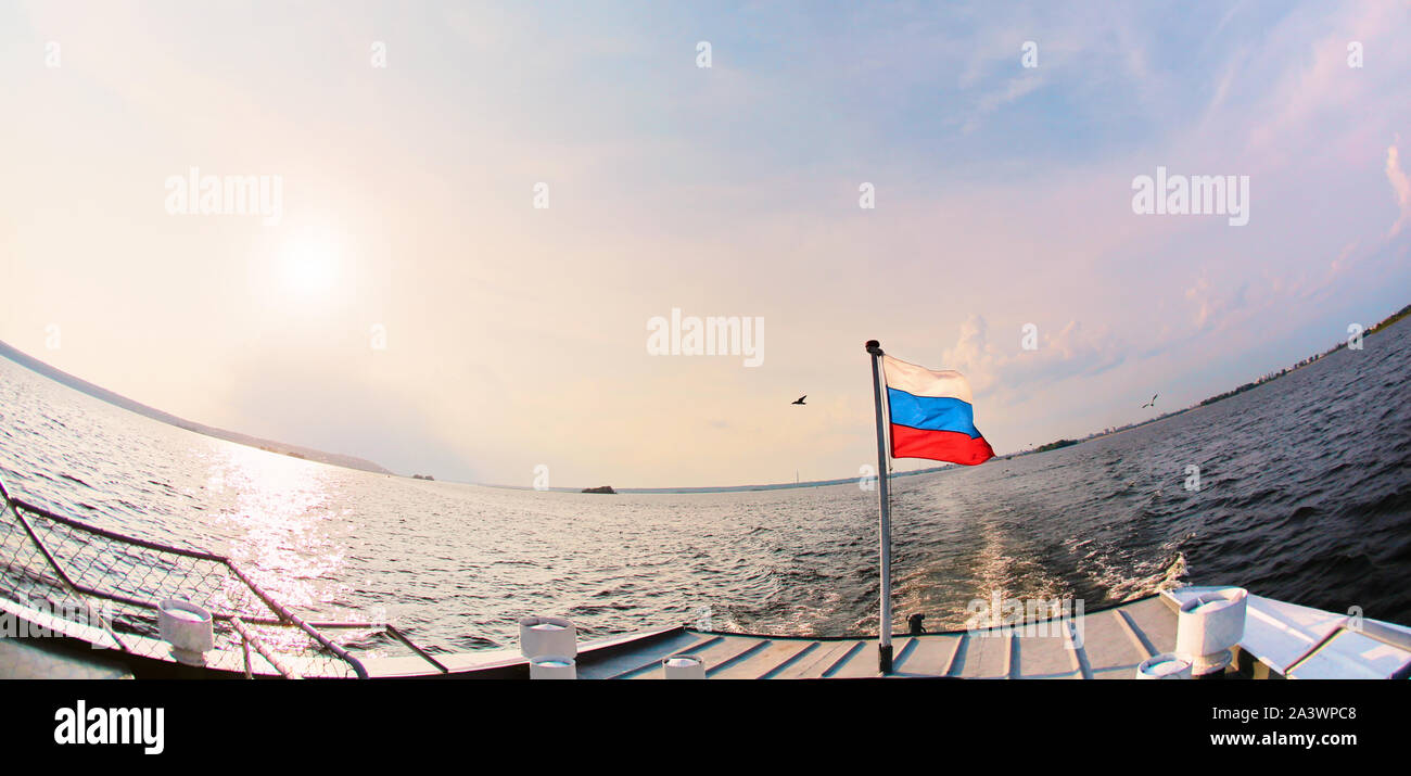 View of waving Russian flag on ship. Against the background of water and blue peaceful sky. The concept of patriotism and love for their homeland Stock Photo
