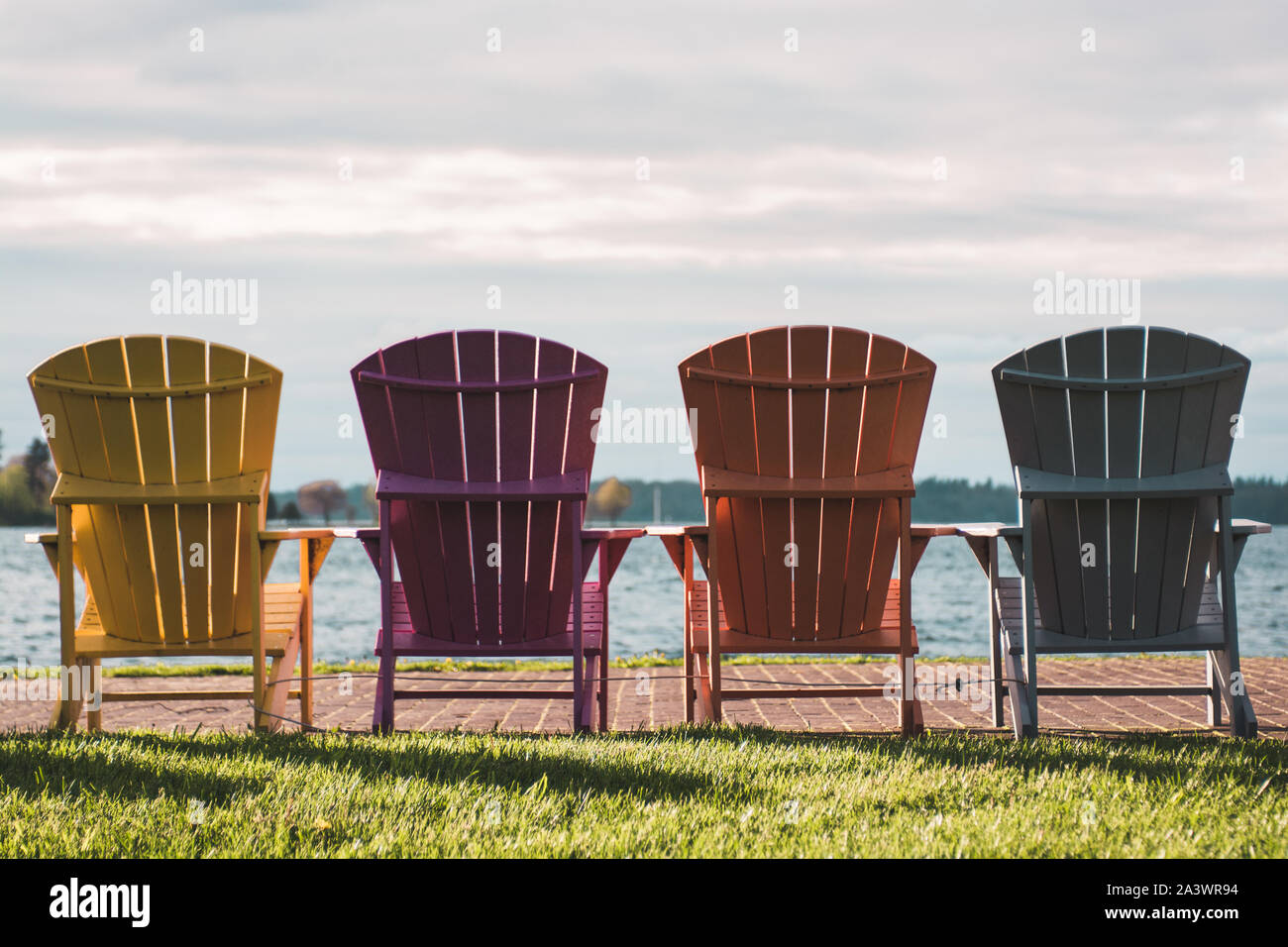 Four colorful lawn chairs face the bay of northern new york in an inviting, relaxing atmosphere