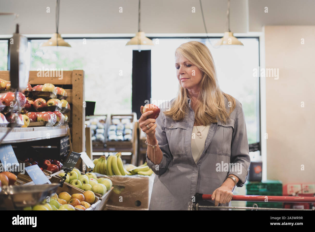 Senior female shopper buying apples in a grocery store Stock Photo