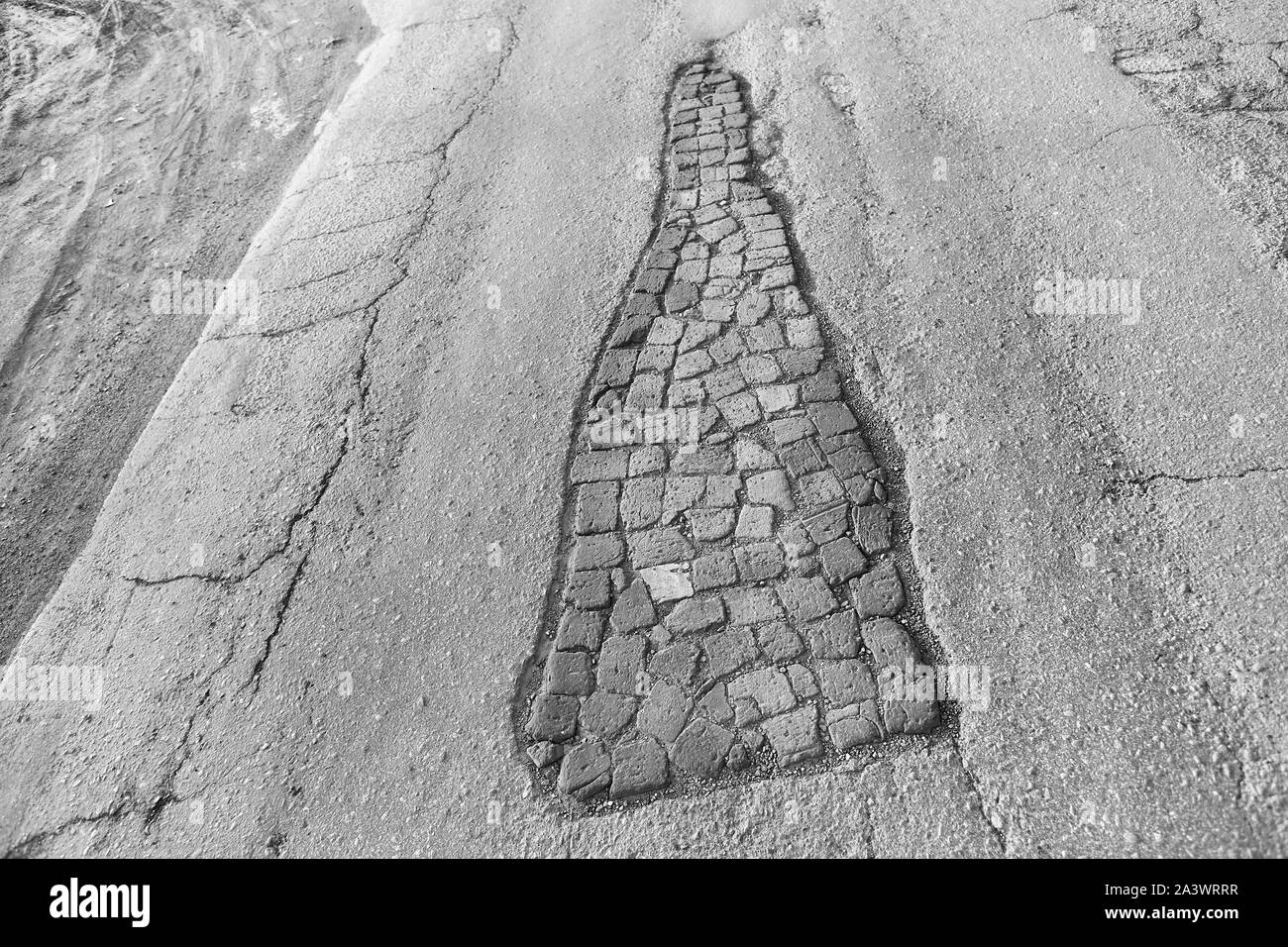 potholes in the road sealed with old bricks. Creative way to repair when there is no money in the budget Stock Photo