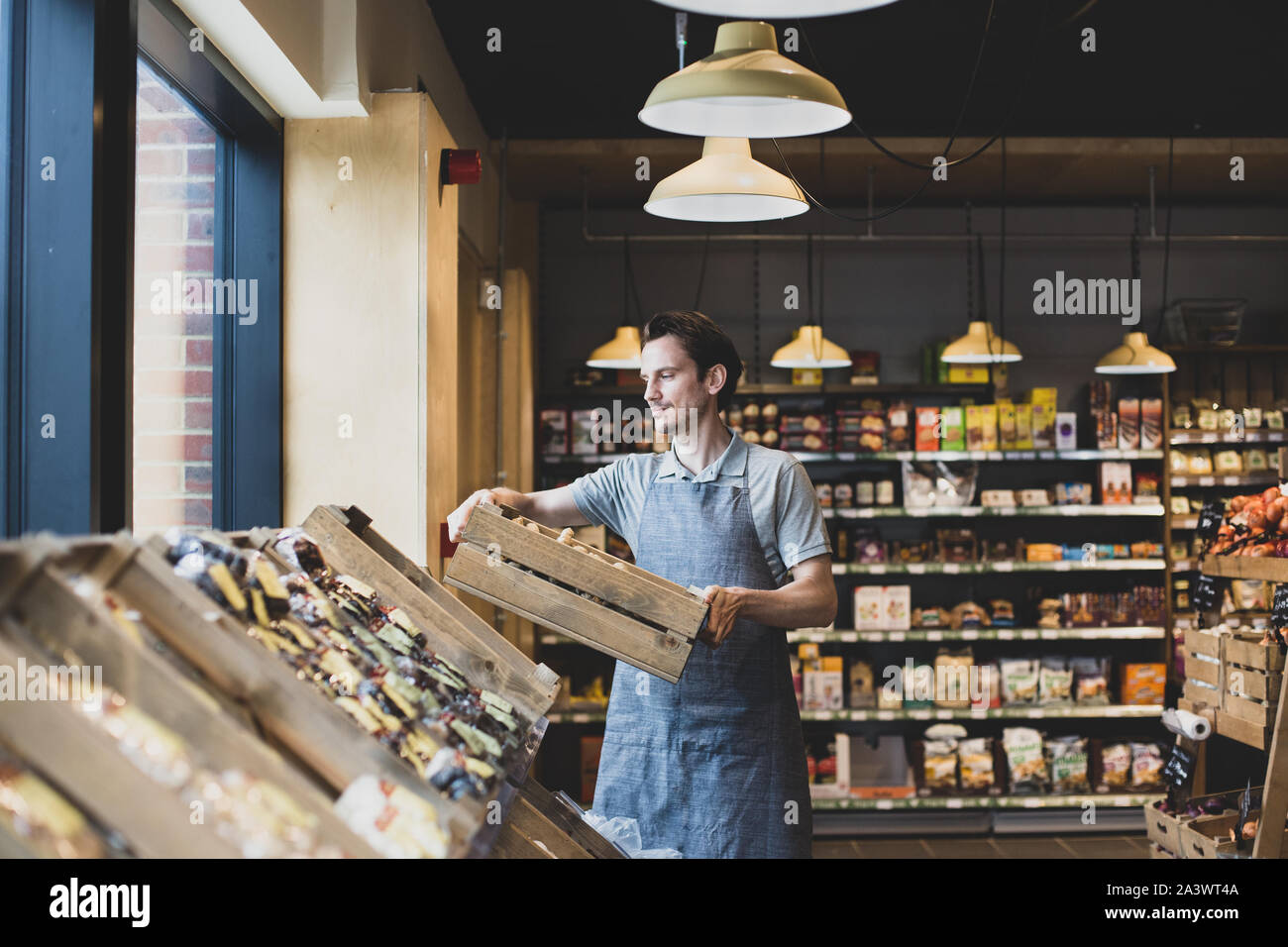 Small business owner of a food market stocking shelves Stock Photo