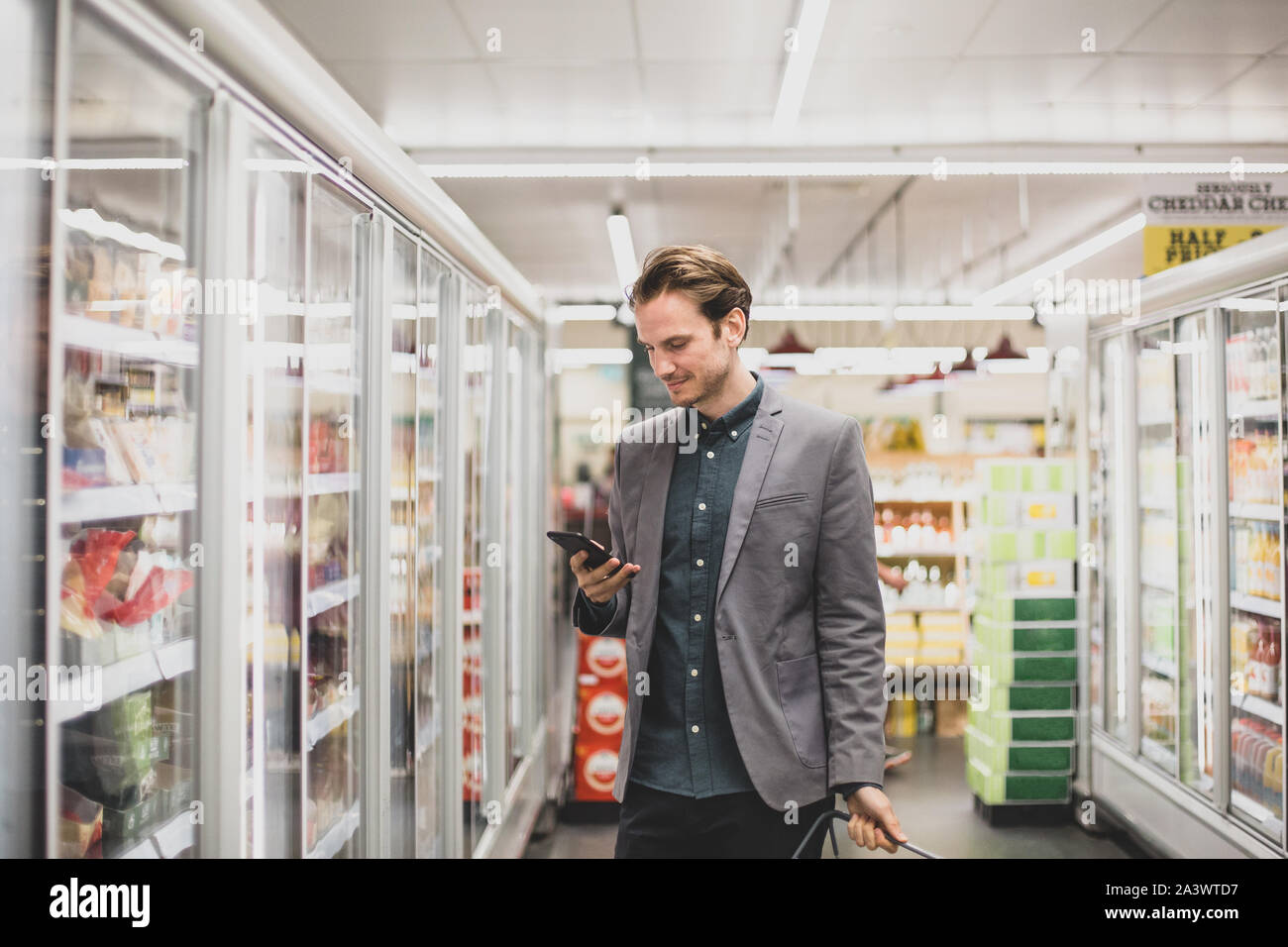 Man looking at smartphone in a grocery store Stock Photo