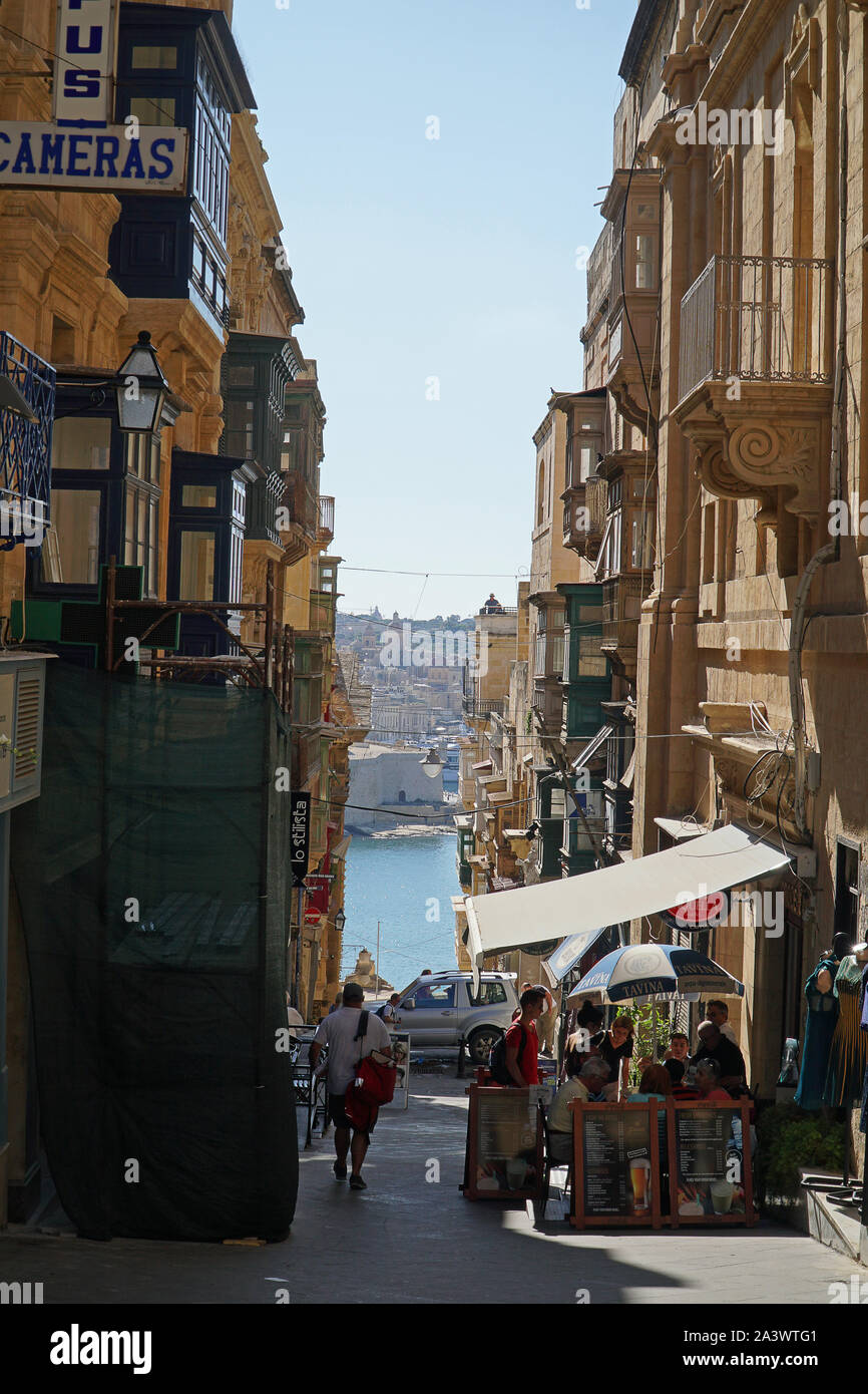 A shop lined street in Valletta, Malta leading down to the harbour Stock Photo
