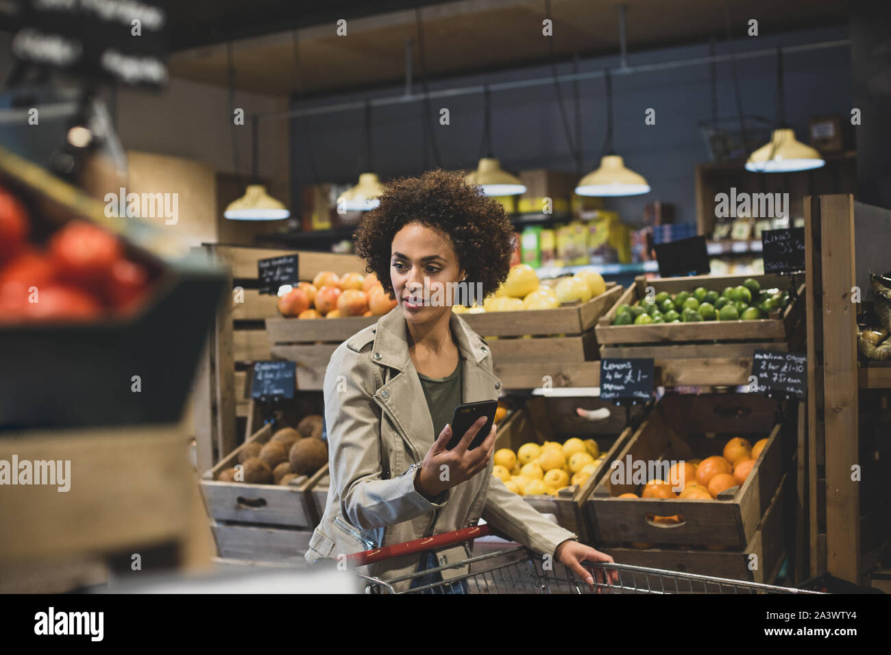 African American female late night grocery shopping and using smartphone Stock Photo