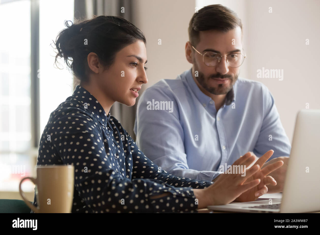 Focused male intern listening to indian mentor explaining online strategy Stock Photo
