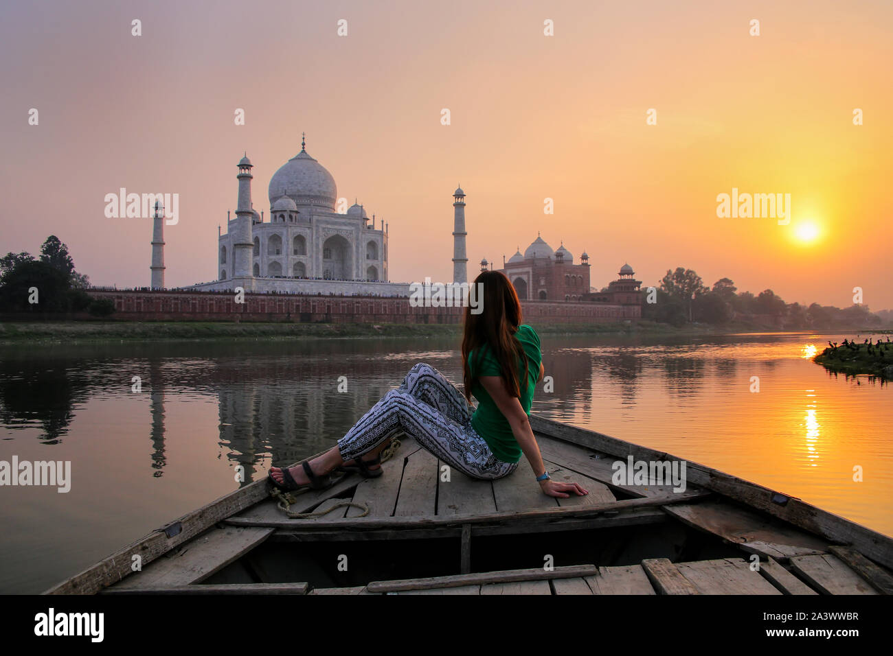 Woman watching sunset over Taj Mahal from a boat, Agra, India. It was build in 1632 by Emperor Shah Jahan as a memorial for his second wife Mumtaz Mah Stock Photo