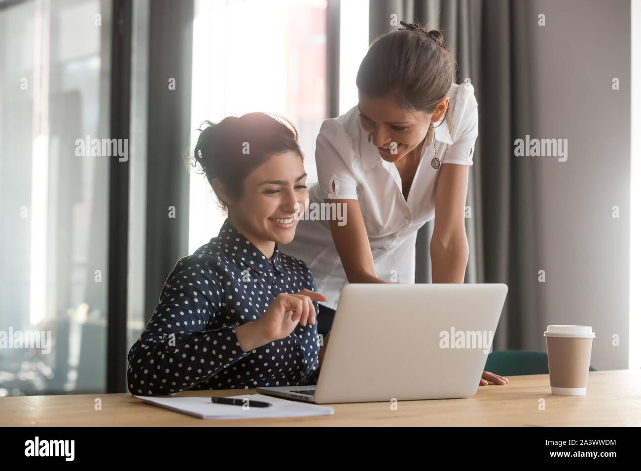 Friendly caucasian mentor supervise indian intern secretary helping with computer Stock Photo