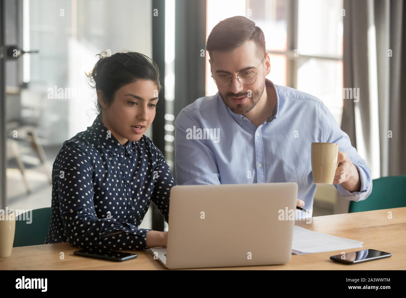 Helpful indian female mentor explaining online project to male intern Stock Photo