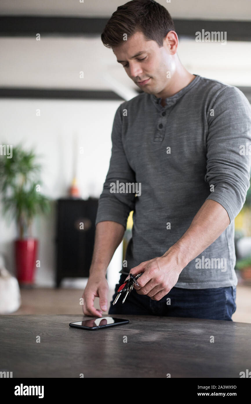 Adult male picking up keys and smartphone from table Stock Photo
