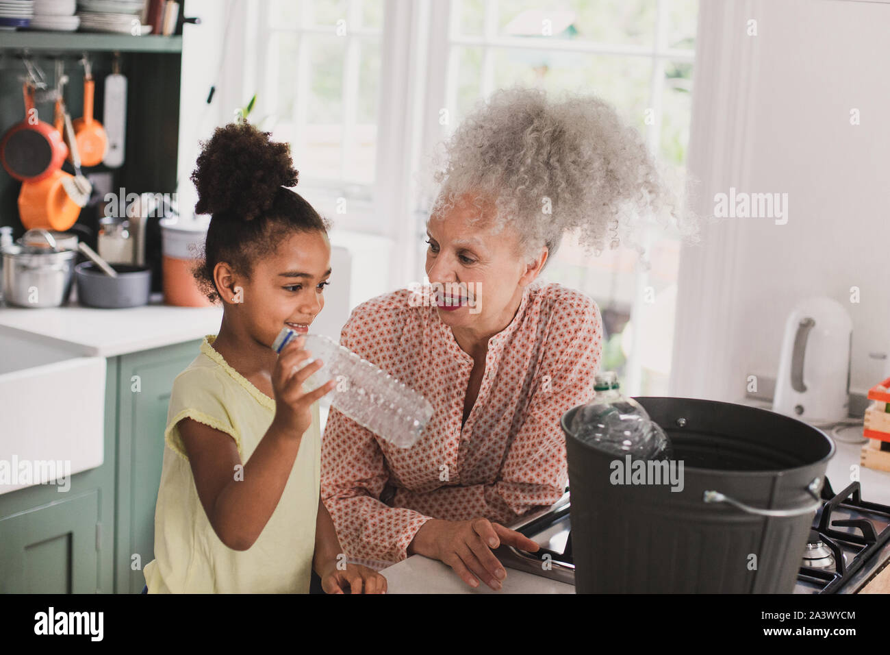 Grandmother recycling at home with granddaughter Stock Photo