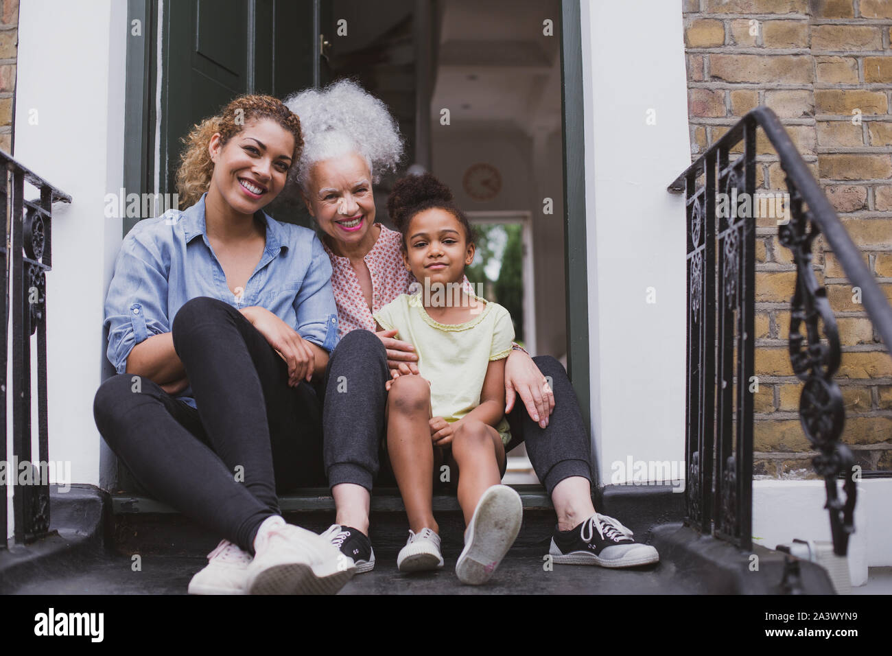 Three generations of women sitting outside family home Stock Photo