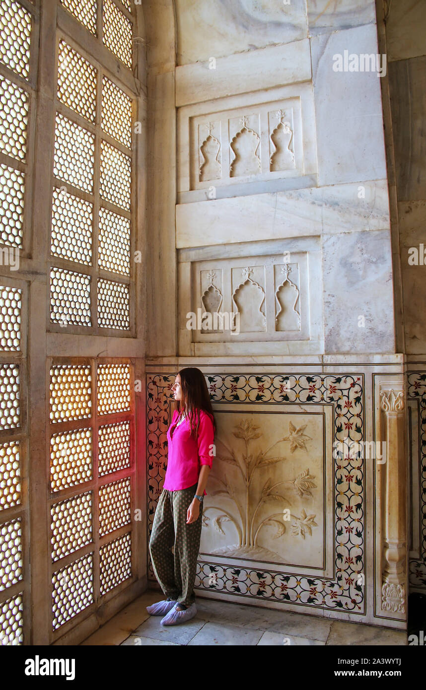 Young woman standing by lattice jali screen inside Taj Mahal, Agra, Uttar Pradesh, India. It was built in 1632 by the Mughal emperor Shah Jahan to hou Stock Photo