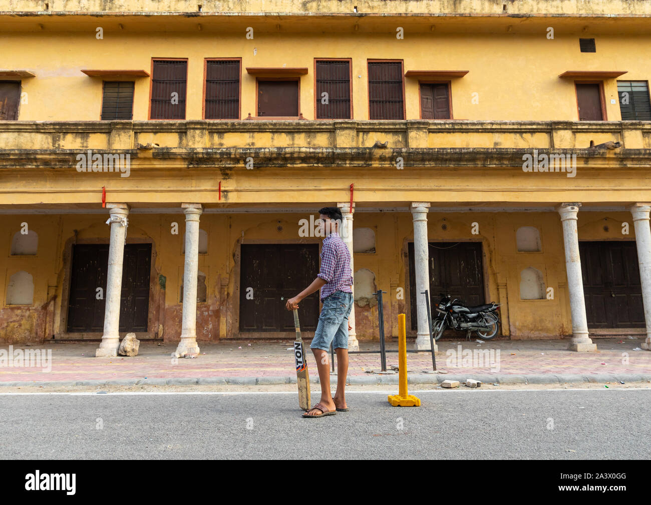 Young boy holding a cricket bat and playing in the street, Rajasthan, Jaipur, India Stock Photo
