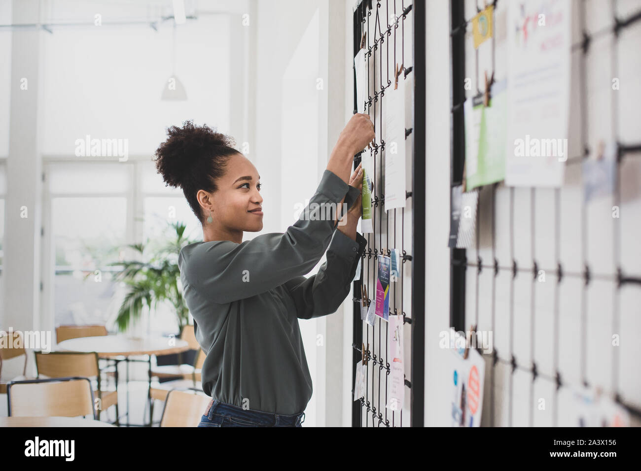 African American businesswoman pinning notice on board Stock Photo