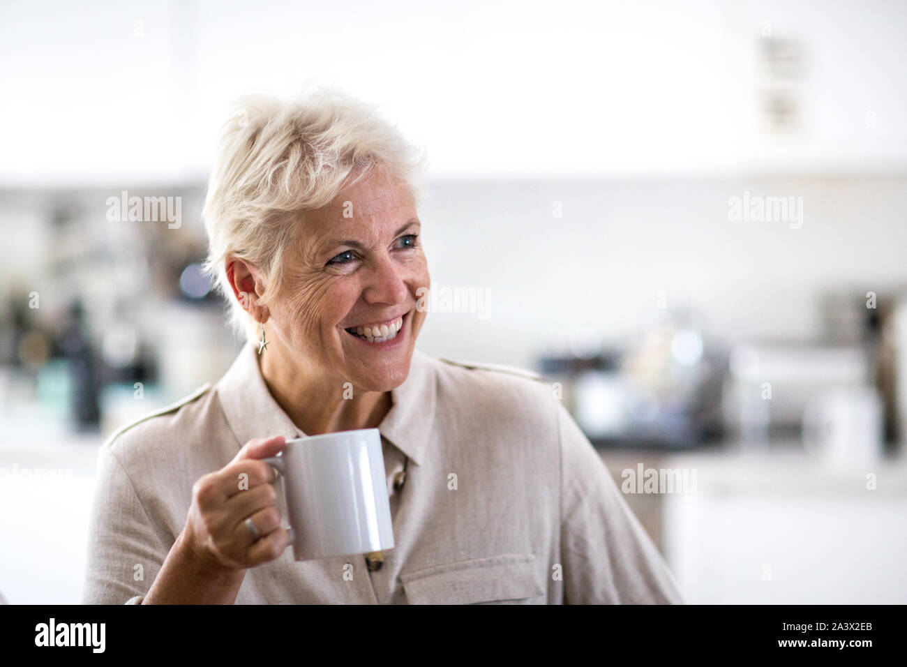 Mature adult woman in conversation holding a mug of tea Stock Photo