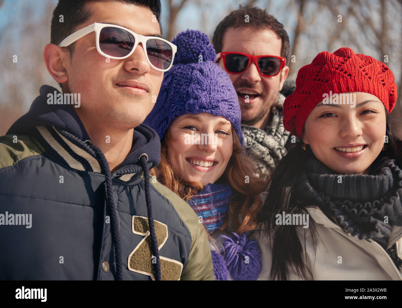 Group of millenial young adult friends photographing each other with a smartphone in a snow filled park Stock Photo