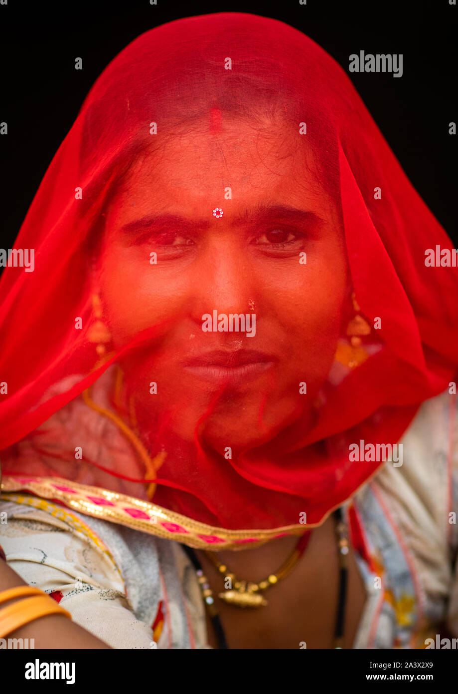 Portrait of a rajasthani woman hidding her face under a red sari ...