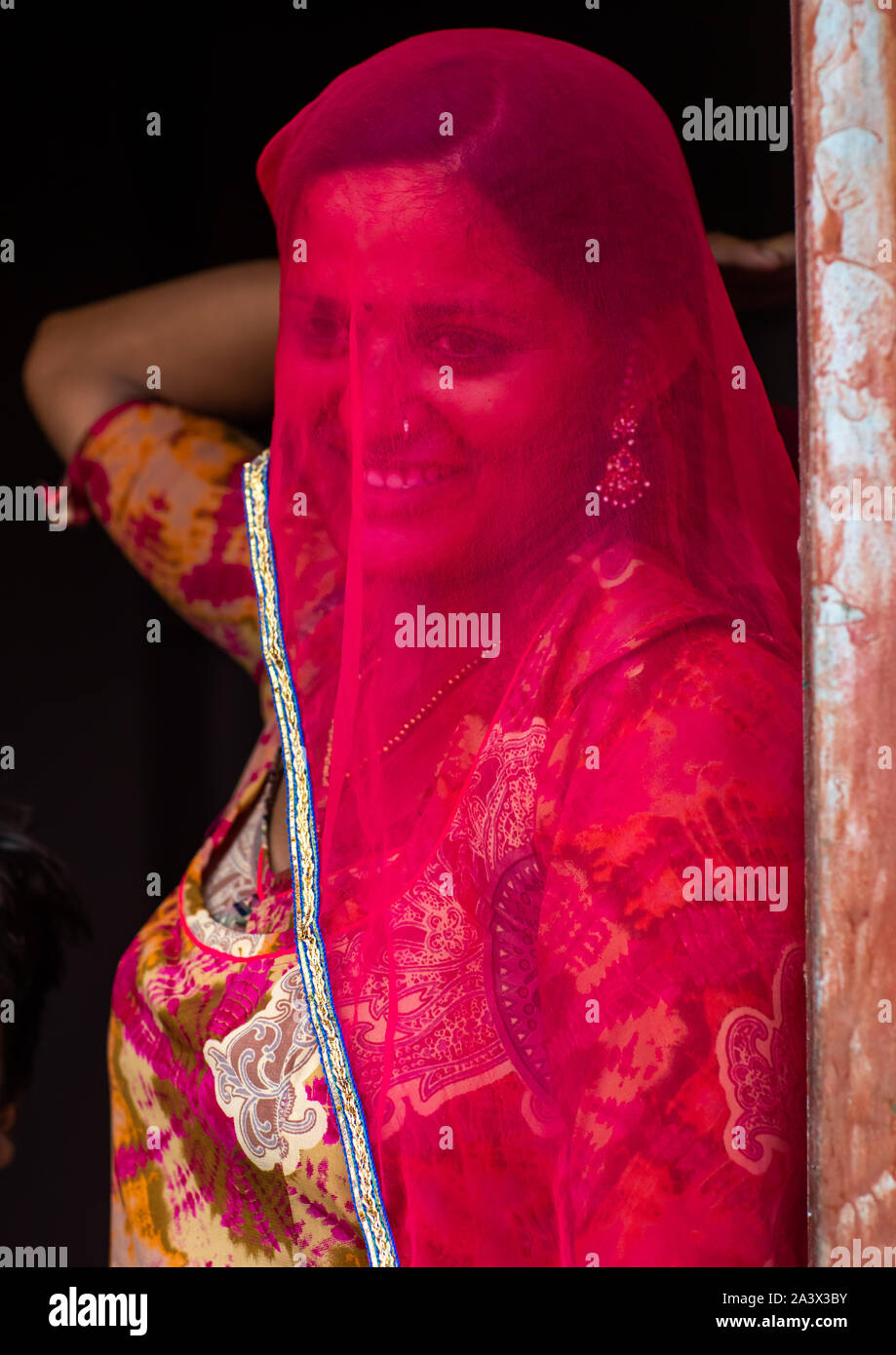 Portrait of a rajasthani woman hidding her face under a red sari ...