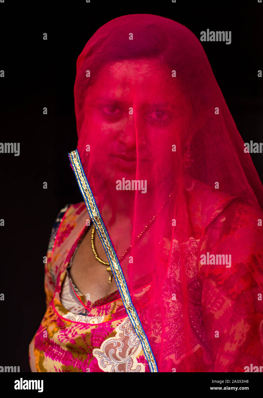 Portrait of a rajasthani woman hidding her face under a red sari ...