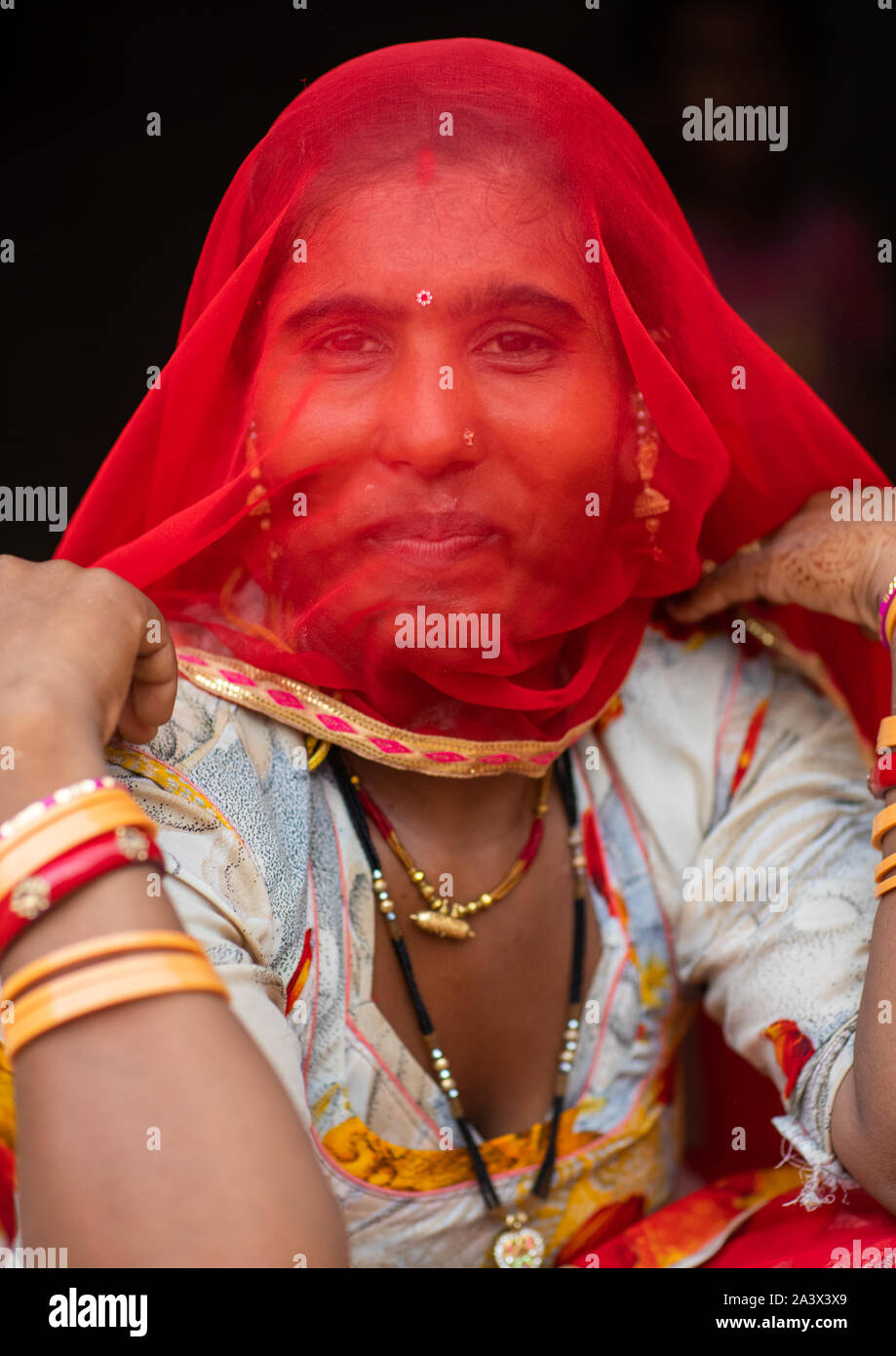 Portrait of a rajasthani woman hidding her face under a red sari ...