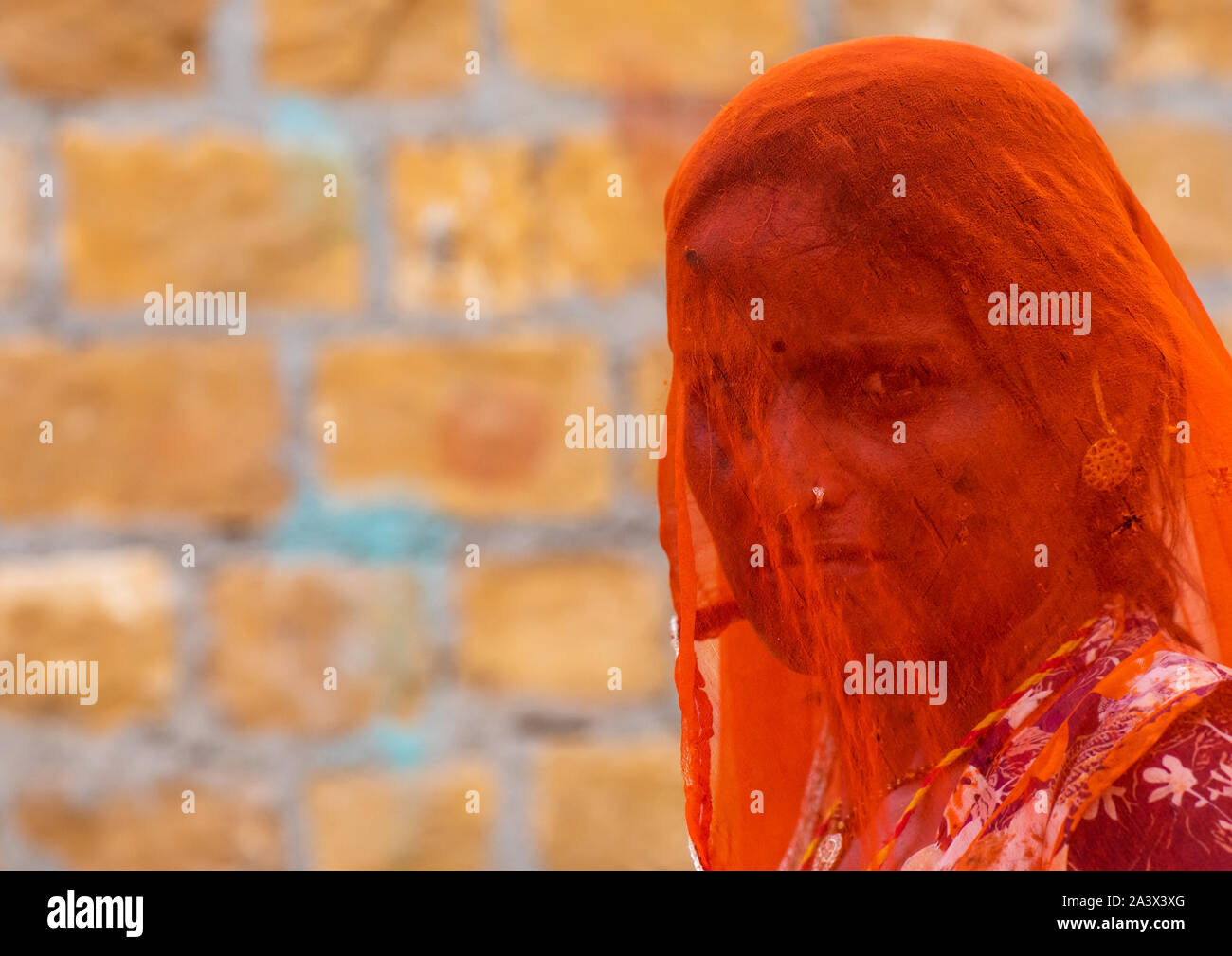 Portrait of a rajasthani woman hidding her face under an orange sari, Rajasthan, Jaisalmer, India Stock Photo