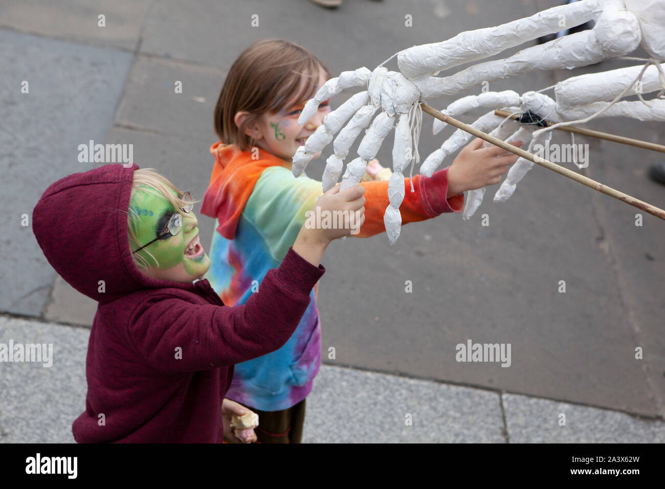 Extinction Rebellion climate protestors continued their occupation of Trafalgar Square for a fourth day, with some super-gluing their hands to the road to block traffic. These children were delighted to shake hands with a skeleton puppet from the XR Bones parade. Stock Photo
