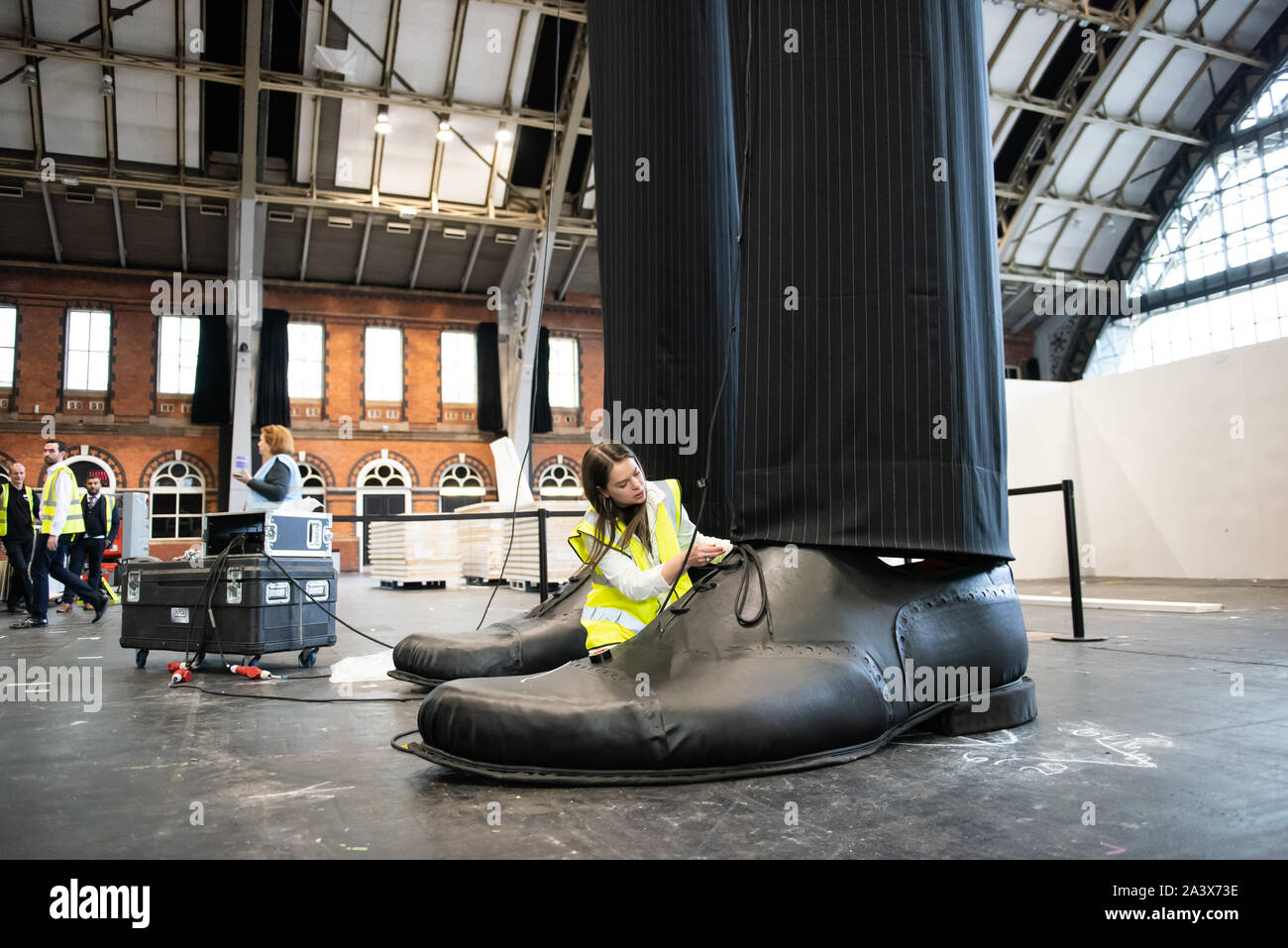 A pair of giant legs known as 'Clandestine' measuring over 10 metres in height are erected at the Aviva Investors Manchester Art Fair at Manchester Central across 11-13th October 2019. The legs are the work of 23 year old Manchester School of Art graduate Millie Sansom. The installation is made from fabric, polystyrene and faux leather and demonstrates the imbalance of power between citizens and political or corporate 'giants'. Stock Photo