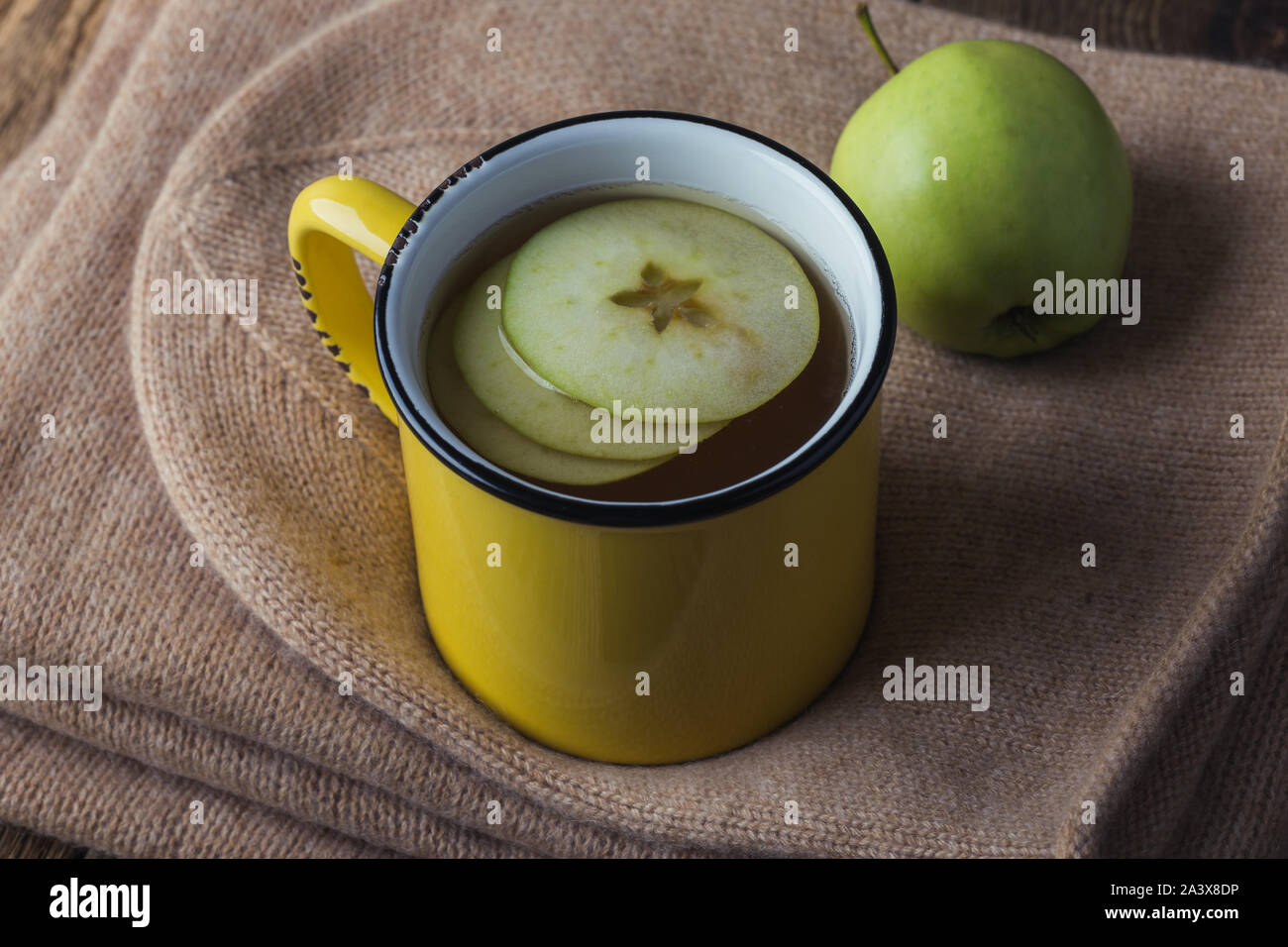 Yellow rural mug with apple hot drink and woolen scarf and socks,  hygge autumn or winter weekend holidays, still life Stock Photo