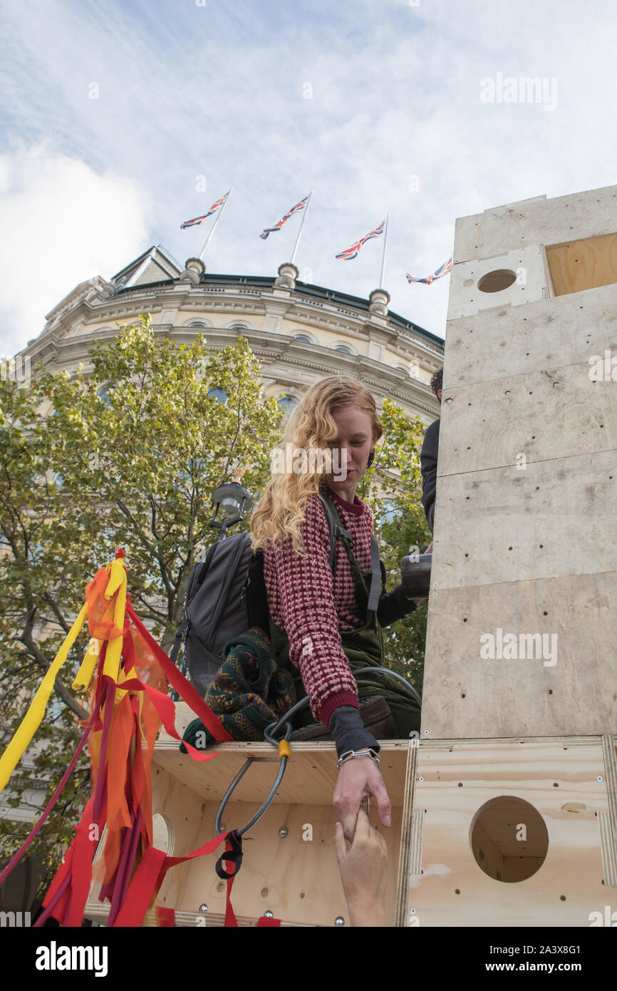 Westminster, London, UK. 10 October 2019. Environmental campaigners Extinction Rebellion have started two weeks protests from 7th to 20th October in and around London to demonstrate against climate change. A demonstrator is chained on to a wooden structure. The protesters in Trafalgar Square demand decisive action from the UK Government on the global environmental crisis. Stock Photo