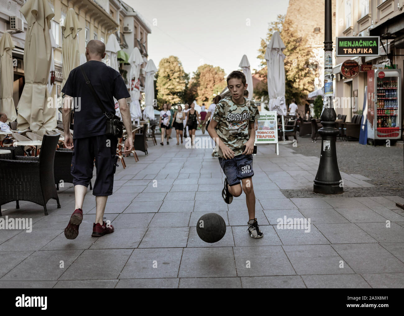 Belgrade, Serbia Aug 2, 2019: Urban scene with a boy leading a ball down the street Stock Photo