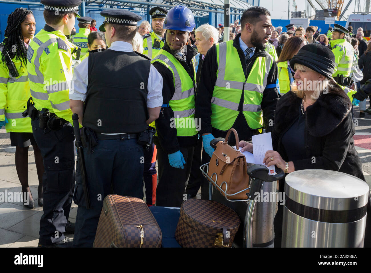 Air passengers find their way through environmental activists protesting about Climate Change during the occupation of City Airport (London's Business Travel hub) in east London, the fourth day of a two-week prolonged worldwide protest by members of Extinction Rebellion, on 10th October 2019, in London, England. Stock Photo