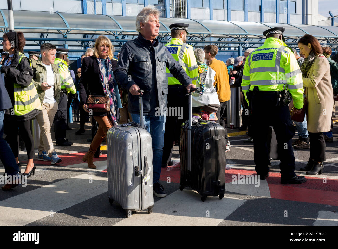 Air passengers find their way through environmental activists protesting about Climate Change during the occupation of City Airport (London's Business Travel hub) in east London, the fourth day of a two-week prolonged worldwide protest by members of Extinction Rebellion, on 10th October 2019, in London, England. Stock Photo
