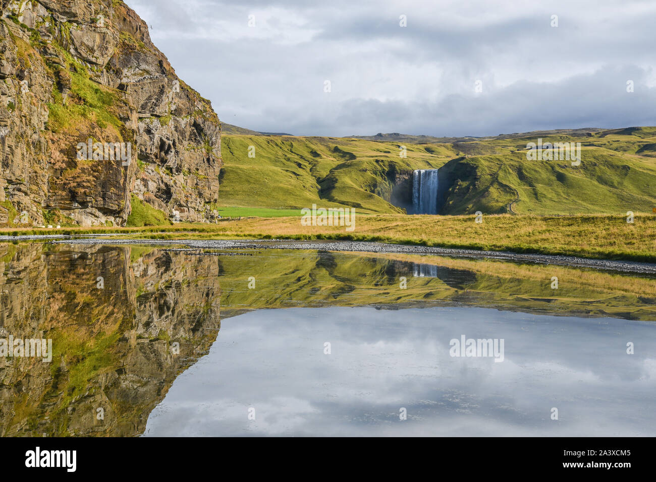 Skogafoss waterfall from distance, with water reflections, Iceland. Stock Photo