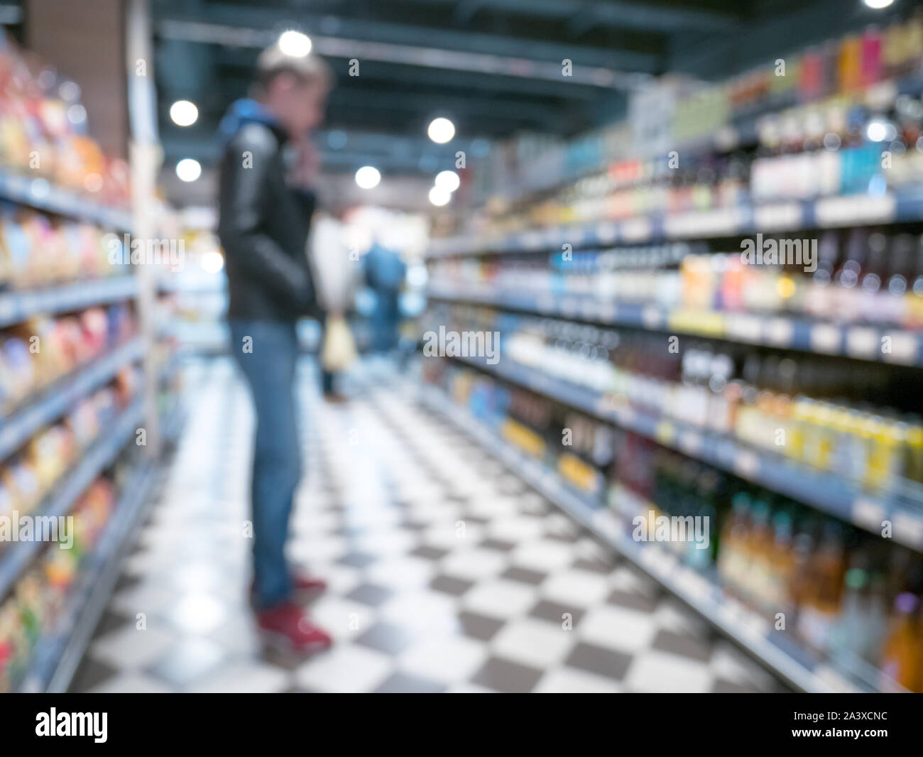 Man chose alcohol in supermarket store blured background with bokeh. Defocused image Stock Photo