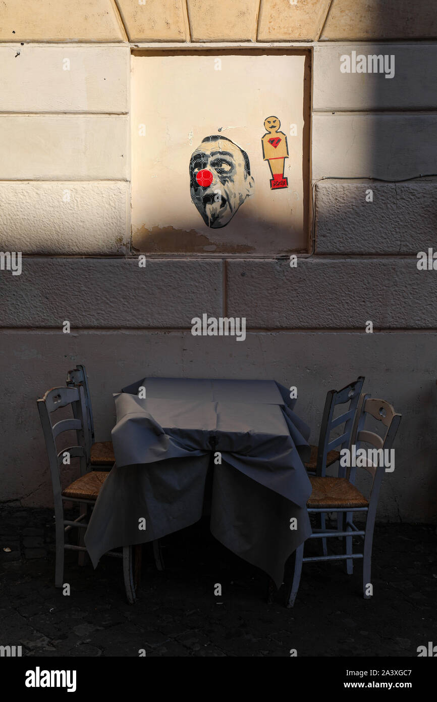 Outdoor seating of a Trastevere restaurant with some street art on the wall in Rome, Italy Stock Photo