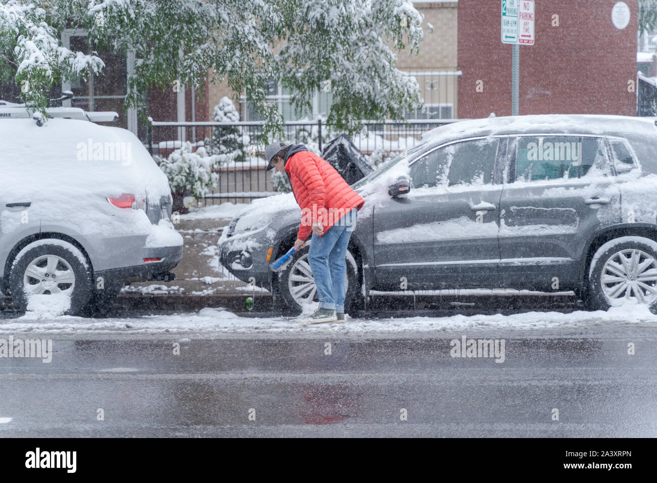 Denver, Colorado, USA- October 10, 2019: Man cleans snow from car during Denver's first snow storm of the season. Stock Photo