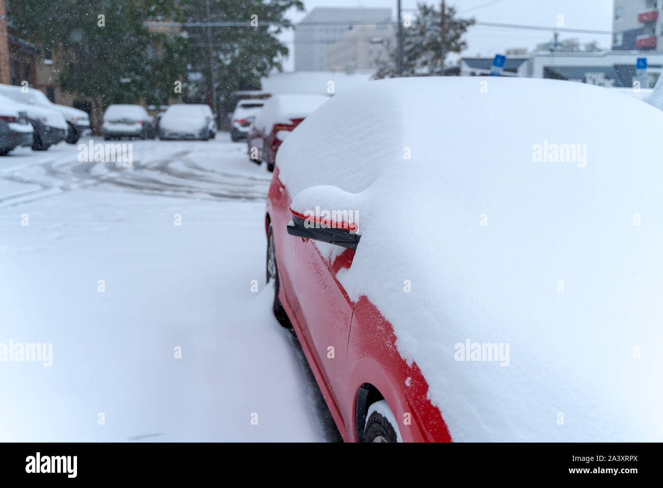 Denver, Colorado, USA- October 10, 2019: Red car covered in snow during Denver's first snow storm of the season. Stock Photo