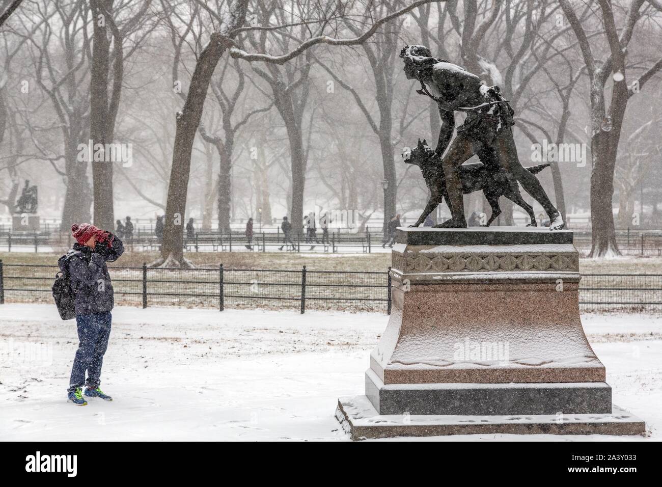 PHOTOGRAPHER IN FRONT OF A STATUE OF A HUNTER WITH HIS DOG, CENTRAL PARK ON A SNOWY DAY, MANHATTAN, NEW YORK, UNITED STATES, USA Stock Photo