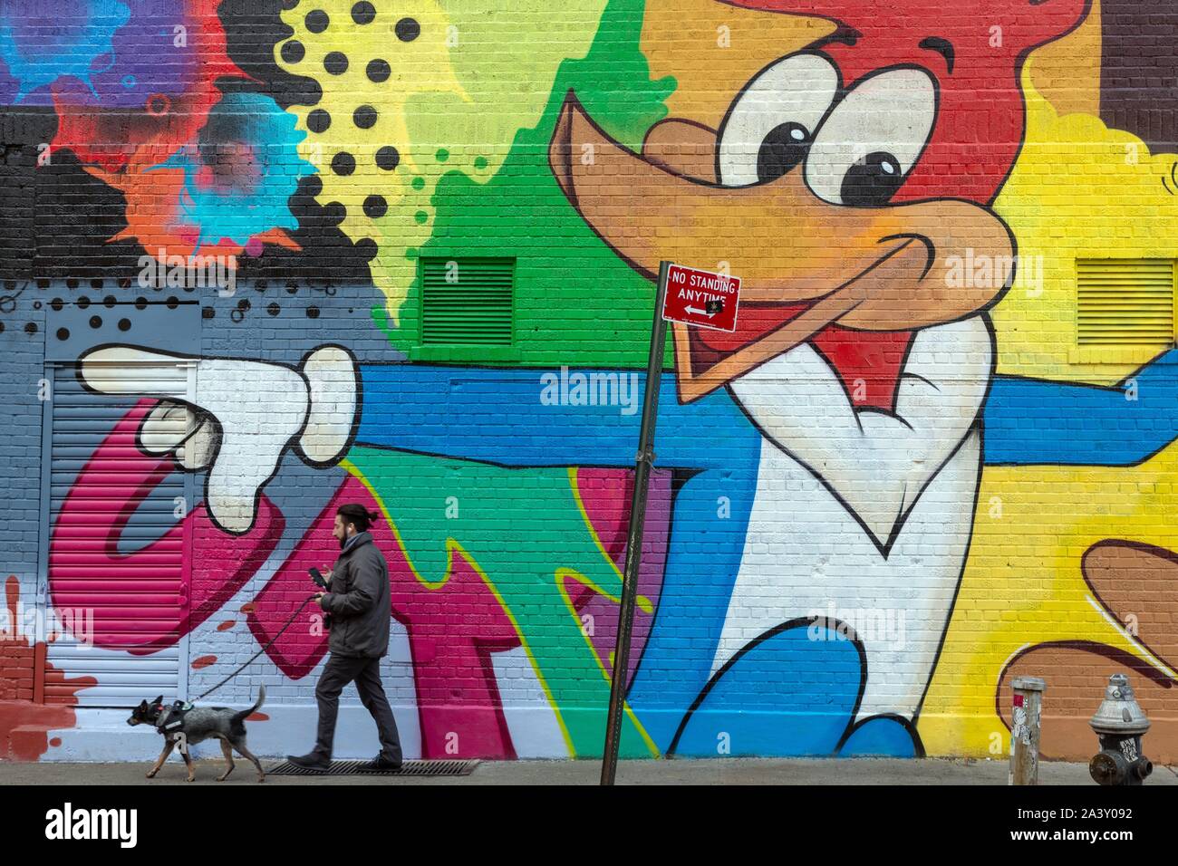 MAN AND HIS DOG IN FRONT OF AN EPHEMERAL MURAL, LITTLE ITALY, MANHATTAN, NEW YORK, UNITED STATES, USA Stock Photo