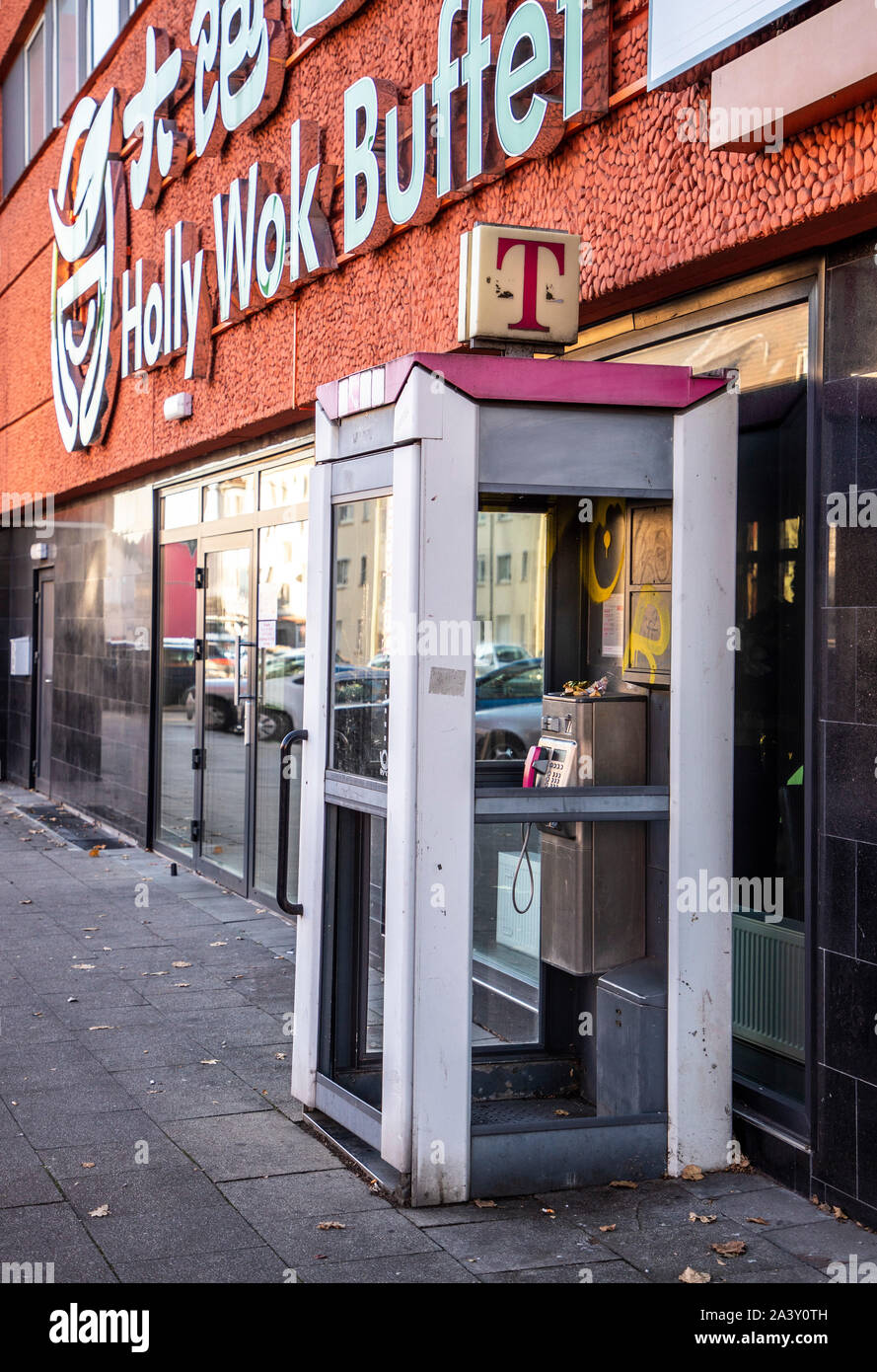 Old telephone booth, the Telekom, out of service, destroyed, on Gladbecker Street in Essen, in front of an Asia Buffet Restaurant, Stock Photo