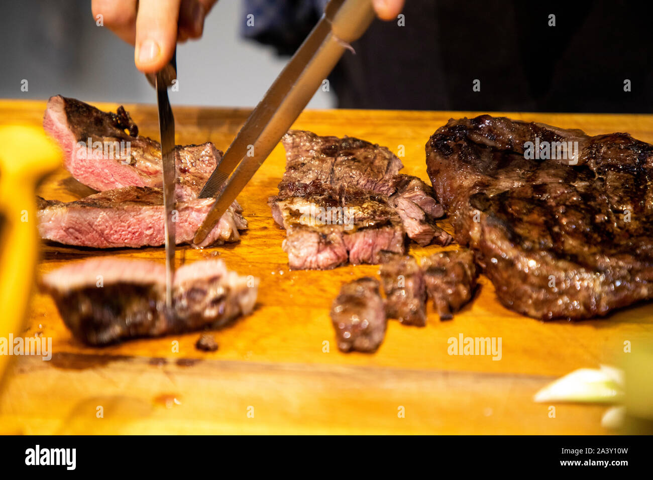 Grilled meat, beef, is cut in portions by the cook, Stock Photo