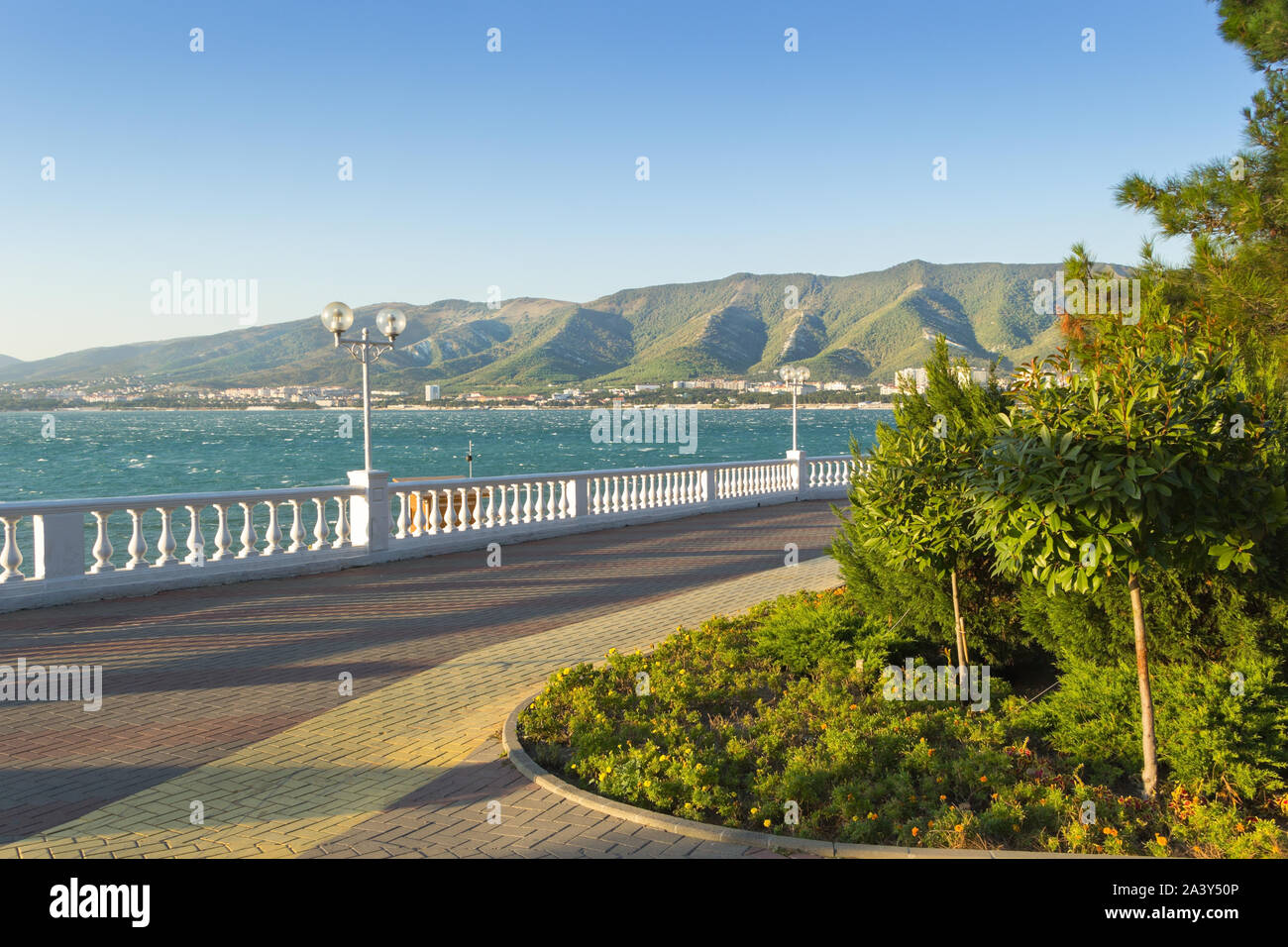 Gelendzhik paved promenade with greenery, lanterns, a balustrade and a bicycle lane. Sunny day during vacation at velvet season. Stock Photo